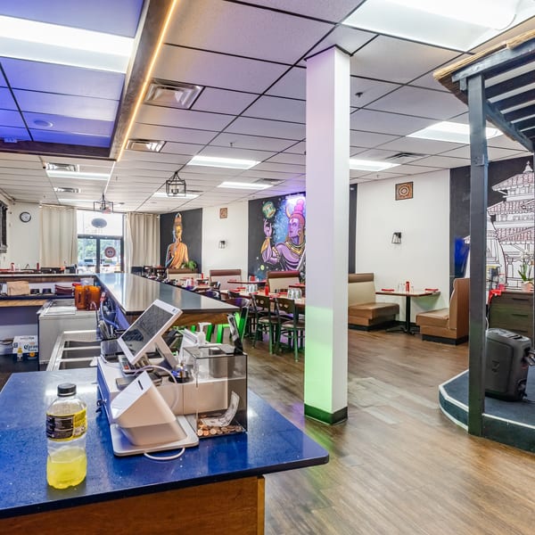 Interior of a restaurant with a bar, dining tables, and colorful murals on the walls.