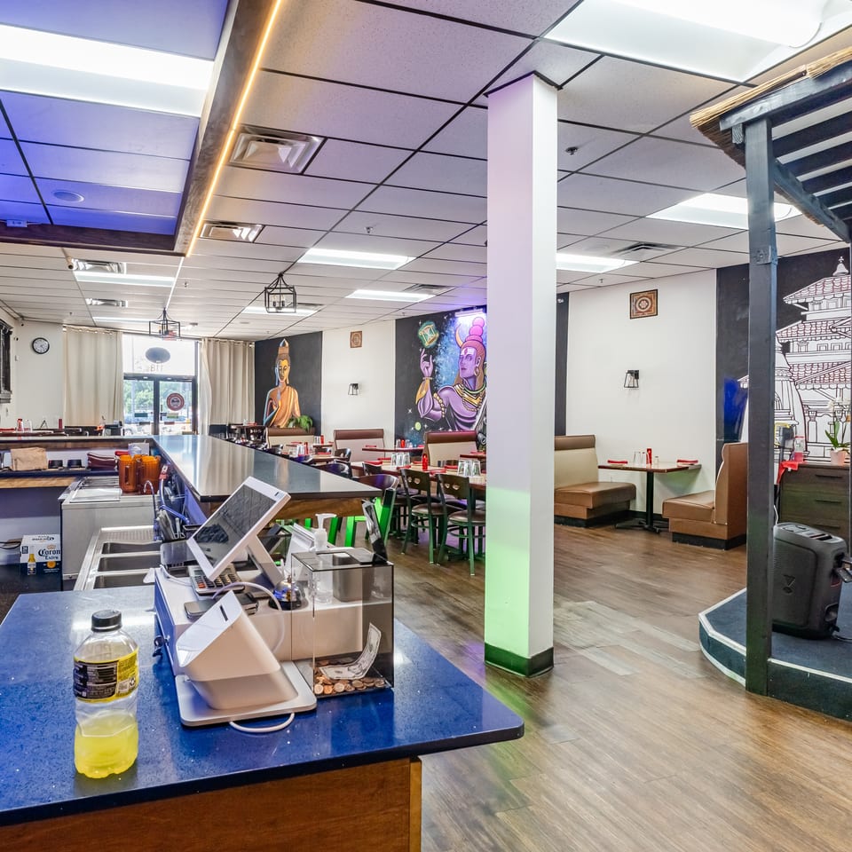 Interior of a restaurant with a bar, dining tables, and colorful murals on the walls.