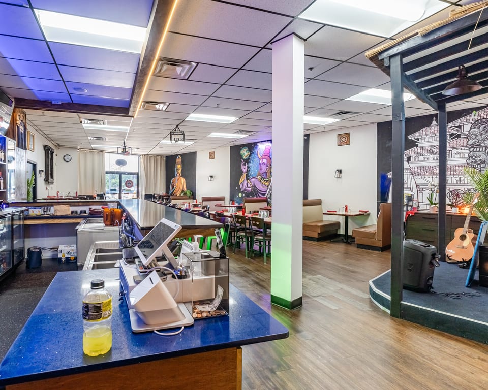 Interior of a restaurant with a bar, dining tables, and colorful murals on the walls.